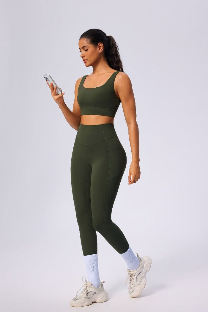 Woman wearing a green athletic outfit holding a phone on a white background