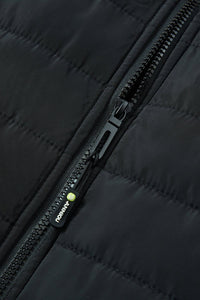 Close-up of a black quilted heated vest with a black zipper and a small green-and-white ANNIOU logo.