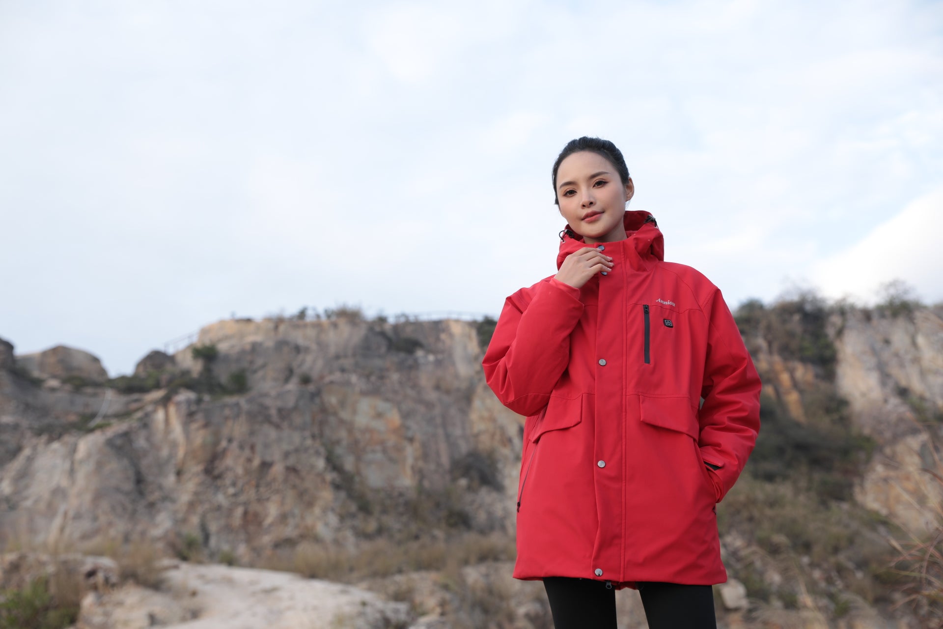 Person wearing a sun protection red jacket standing on a rocky landscape