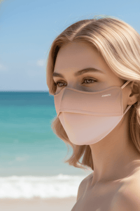 Woman wearing a pink face mask with a beach in the background