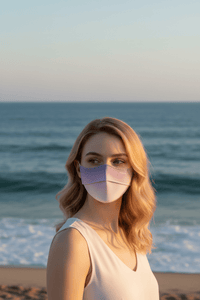 Woman wearing a face mask on a beach with ocean in the background