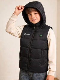 A cute boy wearing a black heated hooded puffer vest over a cream long-sleeve shirt and blue jeans.