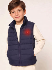 A young boy wearing a navy blue zip-up puffer vest over a cream long-sleeve shirt, standing against a plain light background. The vest features a small glowing red square logo on the left chest.