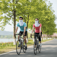 Two people riding bicycles on a path with trees and a lake in the background