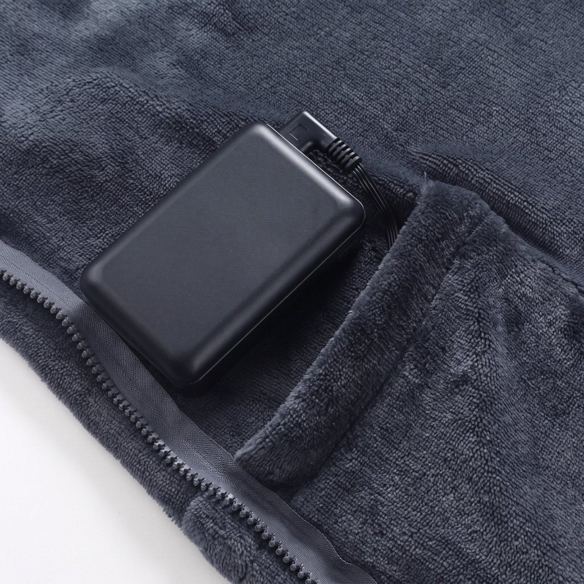 Portable power bank stored in built-in pocket of dark gray wearable heated blanket, USB power supply for heating cape