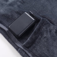 Portable power bank stored in built-in pocket of dark gray wearable heated blanket, USB power supply for heating cape