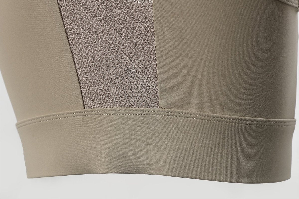 Beige sports bra with mesh panel on a light gray background