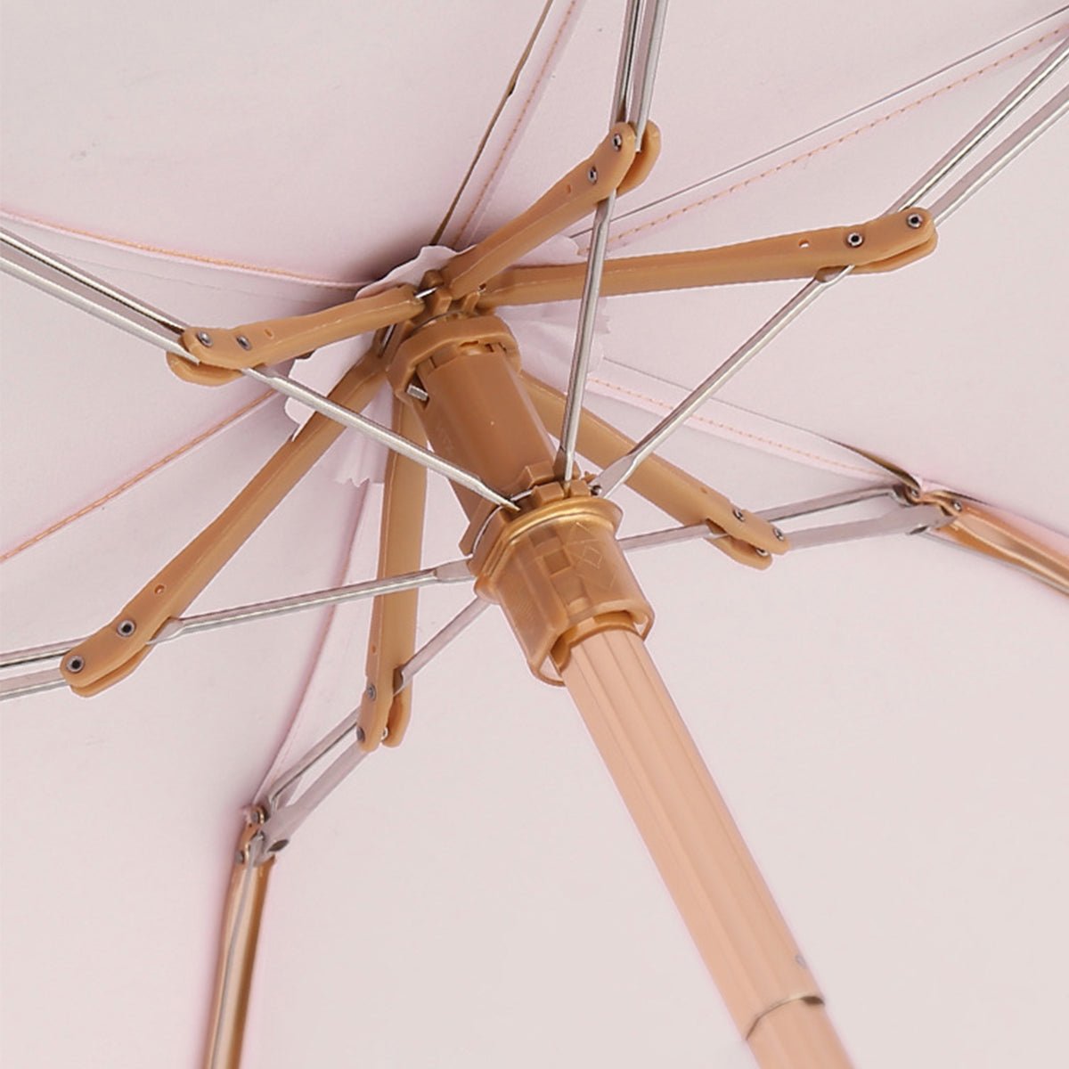 Close - up of an umbrella's metal frame on a light pink background