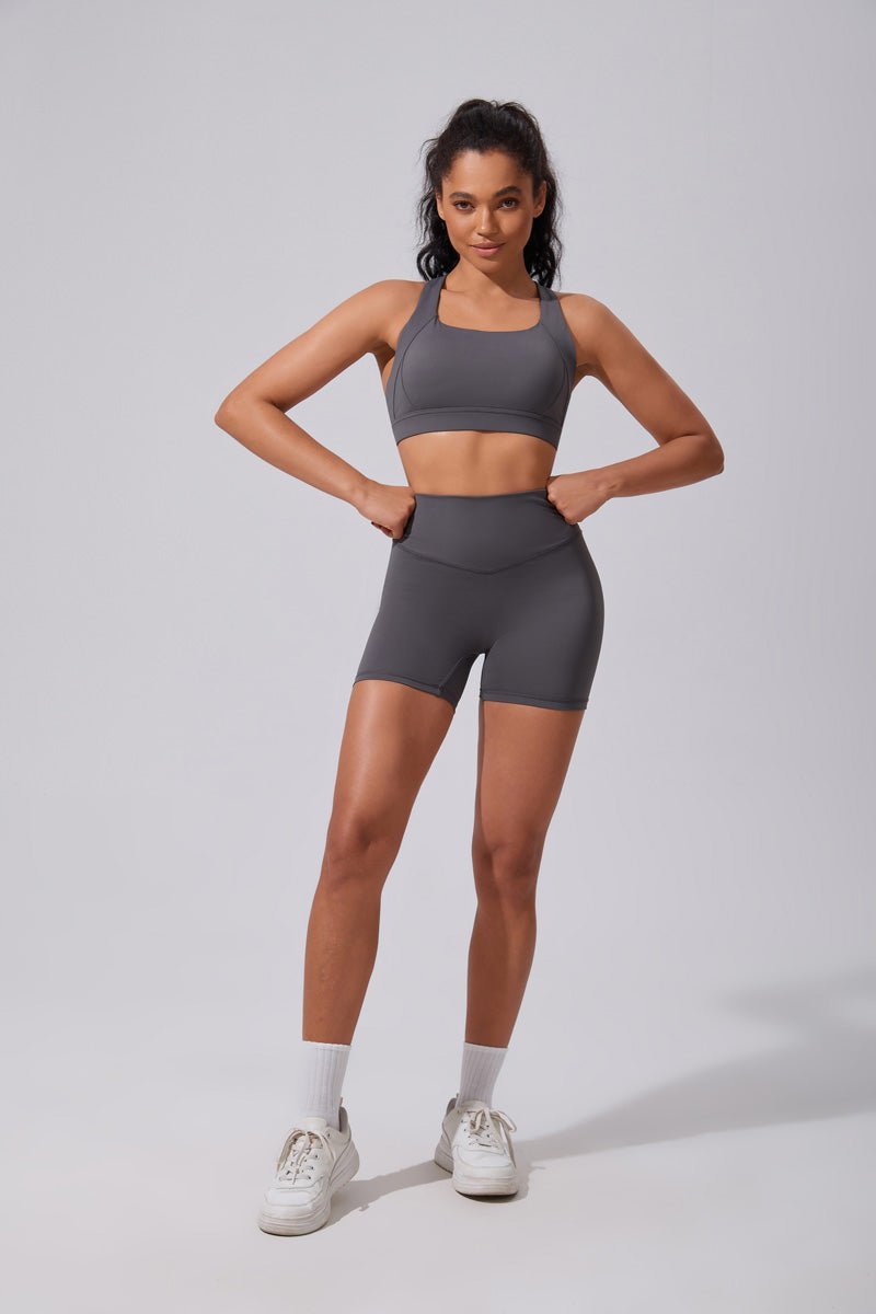 Woman wearing a gray athletic outfit on a plain background