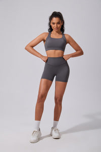 Woman wearing a gray athletic outfit on a plain background