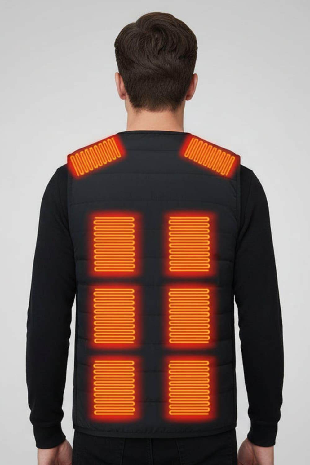 A man viewed from the back wearing a black quilted vest with 8 heat sections on the back and shoulder straps.