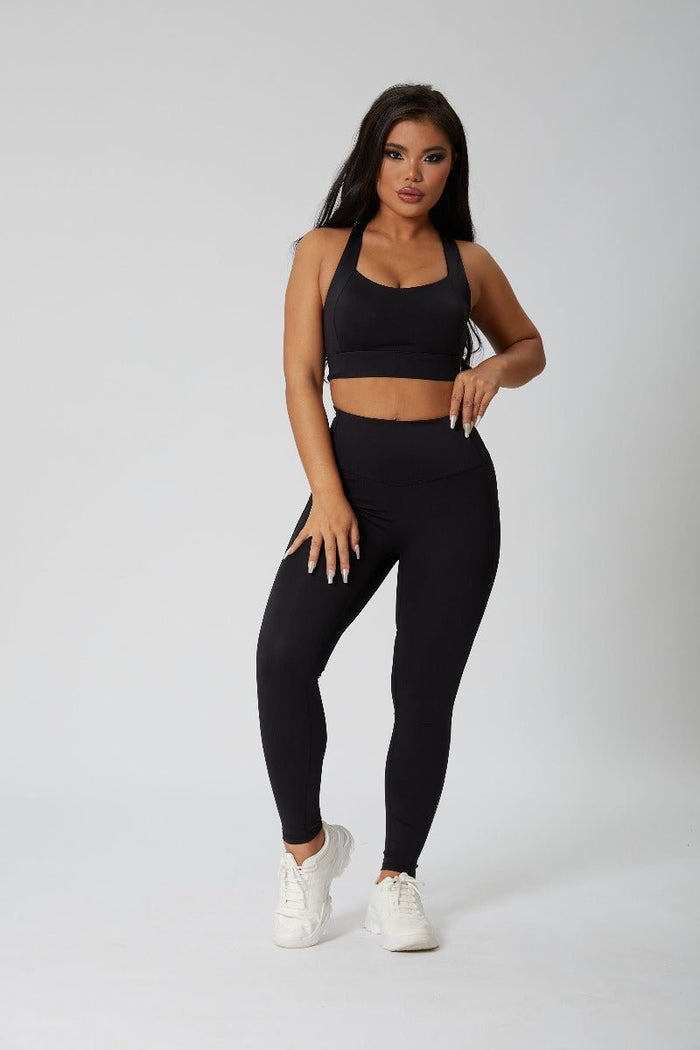 Woman wearing a black sports bra and leggings set on a white background