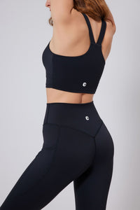 Person wearing a black sports bra and leggings on a light gray background UPF 50+