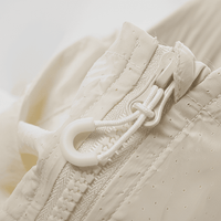 Close - up of a beige textured fabric with a zipper and white pull tab.