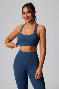 Woman wearing a blue sports bra and leggings on a plain background