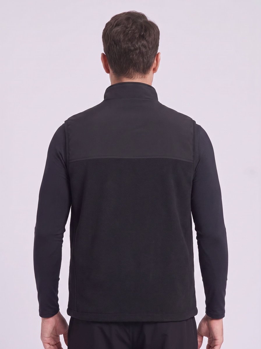 A man viewed from the back wearing a black long-sleeve quarter-zip fleece gilet, set against a plain light gray studio background.
