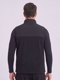 A man viewed from the back wearing a black long-sleeve quarter-zip fleece gilet, set against a plain light gray studio background.