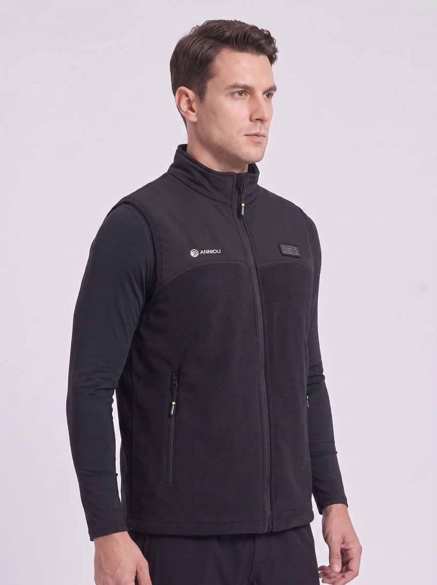 A man wearing a black zip-up fleece heated vest over a black long-sleeve shirt.