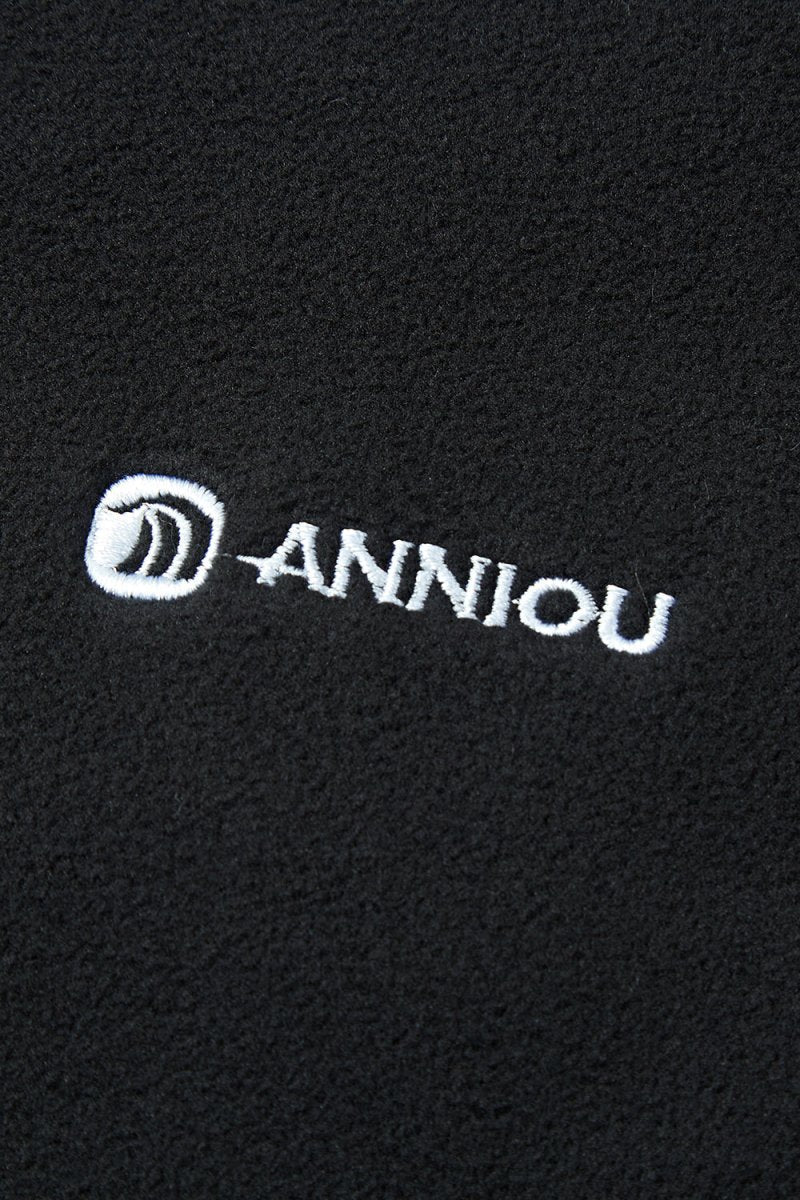 Close - up of a black fabric with 'Anniou' logo embroidered in white.
