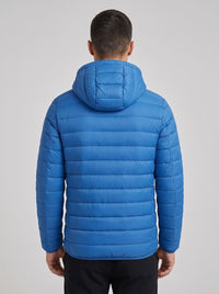 A man viewed from the back wearing a bright blue hooded puffer jacket, shown against a plain light gray studio background.
