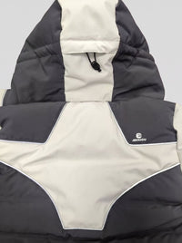 A close-up of a ski puffer jacket with a color-blocked design in dark gray and off-white. The hood is up, and a small white 'ANNIOU' logo is visible on the right side.