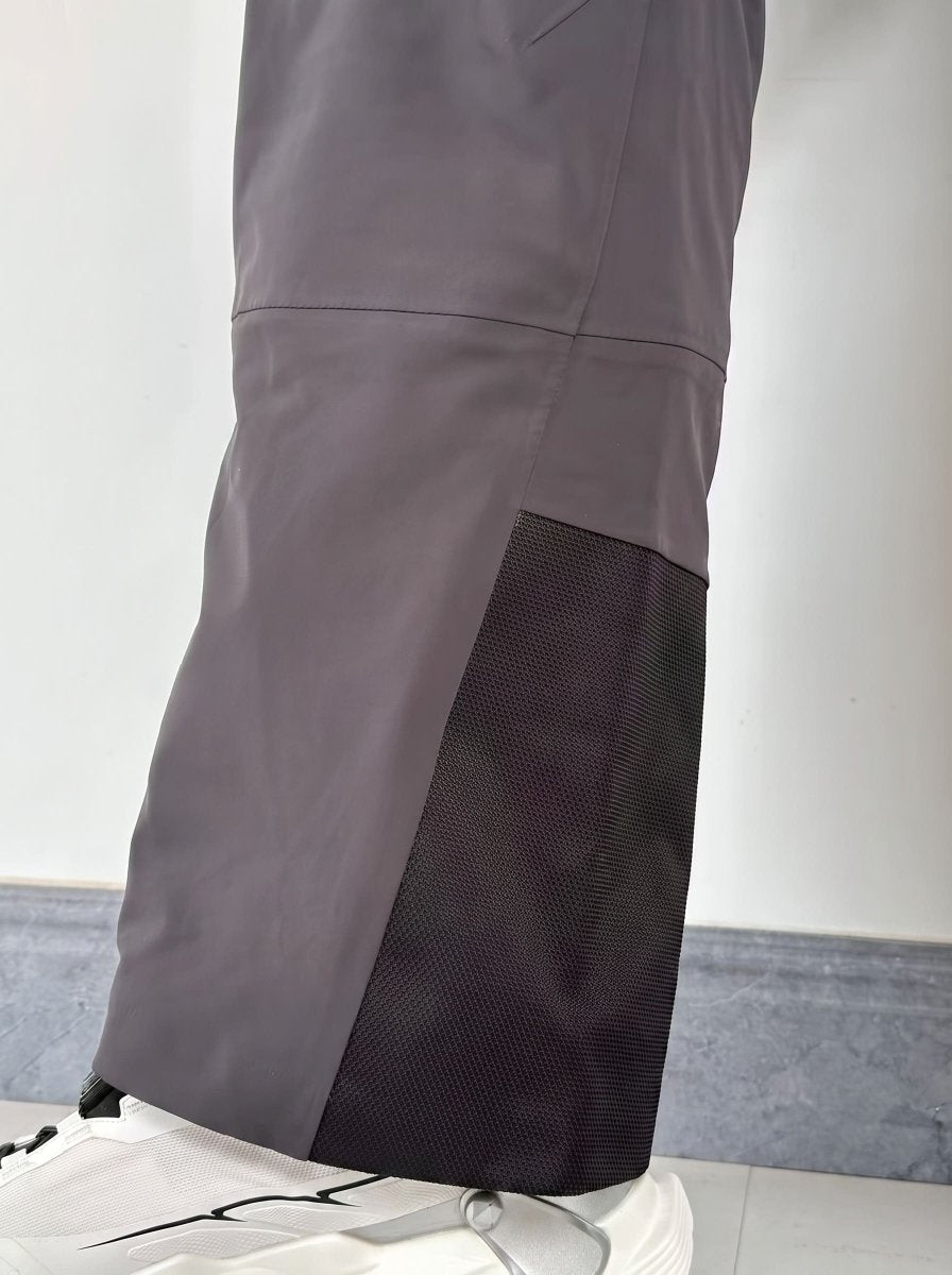 Close-up of the lower leg of a man wearing gray ski pants with a black mesh panel