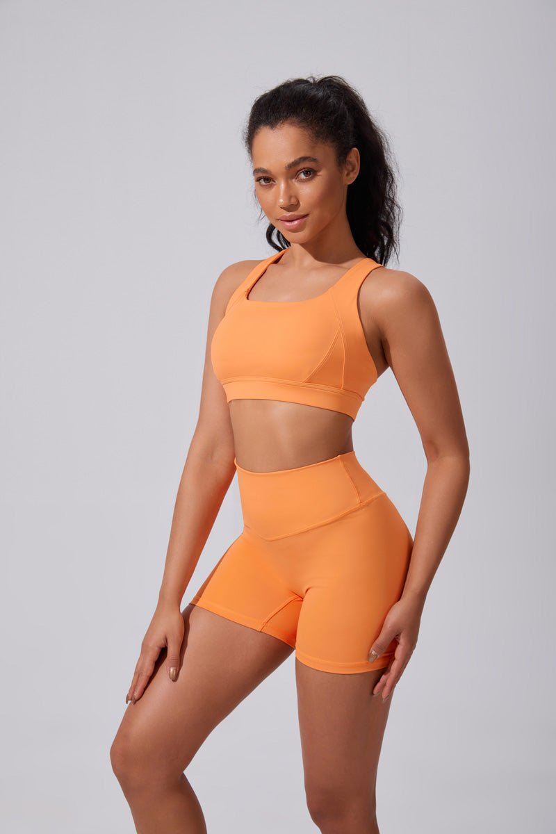 Woman wearing an orange sports outfit on a gray background