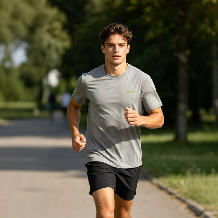 A man wearing a gray quick - drying T-shirt is jogging in the park.