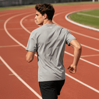 The image shows the back of a gray quick - drying T-shirt, with a sports field in the background.