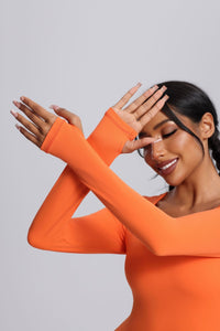 Woman wearing an orange long - sleeve thumbhole jumpsuit