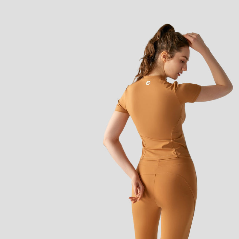 Woman wearing a brown sun protection UPF 50+ Yoga T-shirt and leggings with a logo on a white background