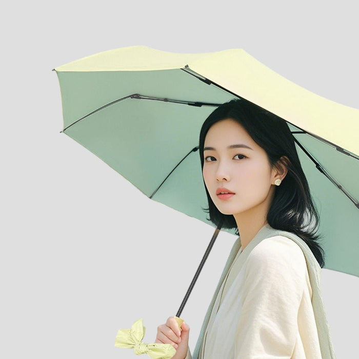 Woman holding a light green Sun Protective Bow Umbrella against a plain background