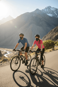 Two cyclists on a mountain road with sun protection face masks on