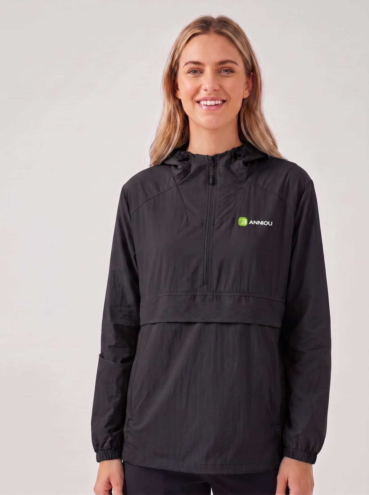 A woman wearing a black hooded lightweight jacket with a front zipper and a small green and white Annou logo on the left chest, photographed against a plain light gray studio background.