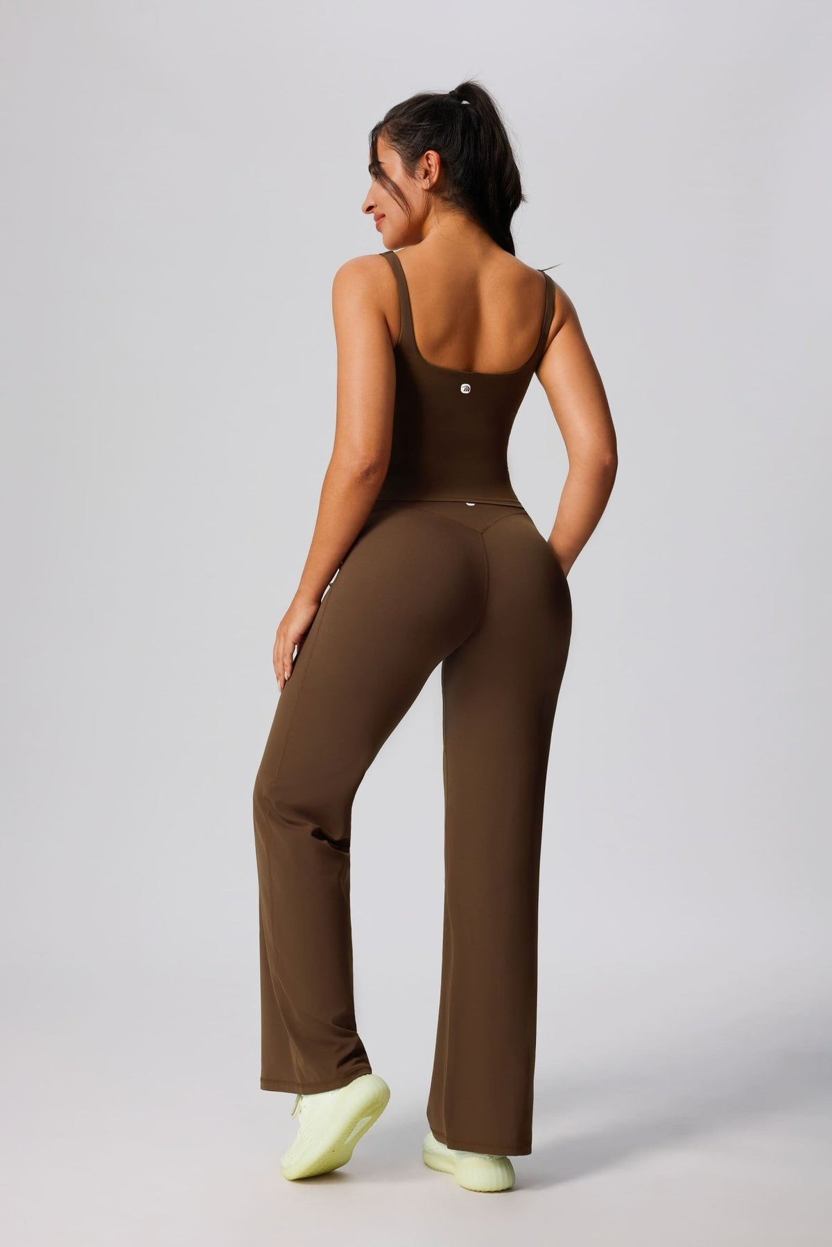 Woman wearing a brown jumpsuit on a plain background
