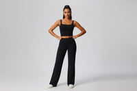 Woman wearing a black outfit with wide - leg yoga pants on a plain background