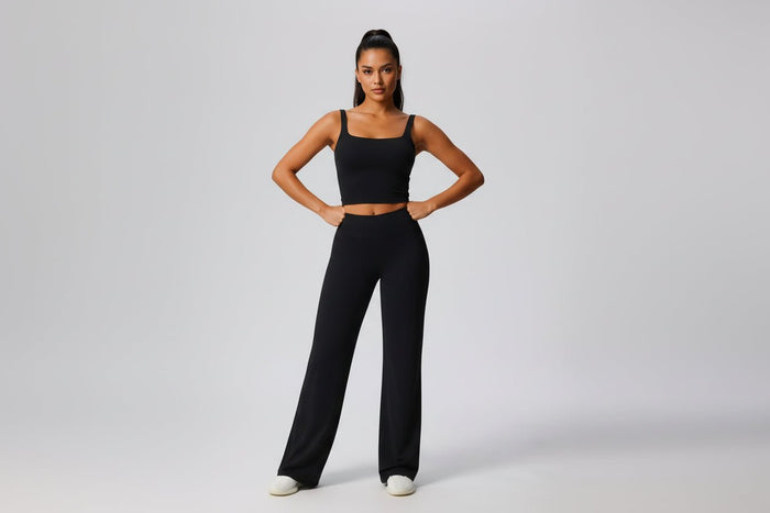 Woman wearing a black outfit with wide - leg yoga pants on a plain background