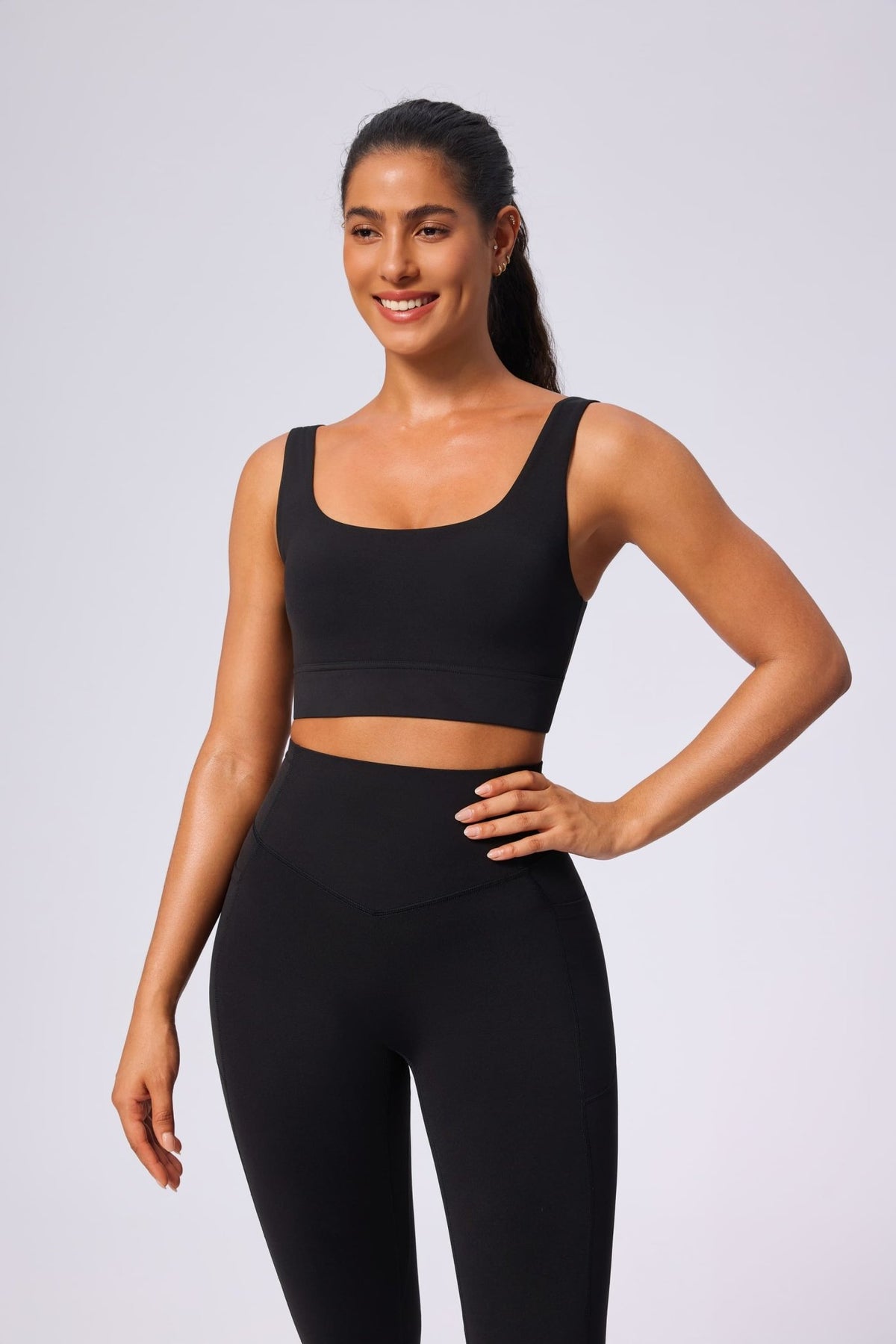 Woman wearing a black yoga sports bra and leggings on a light gray background