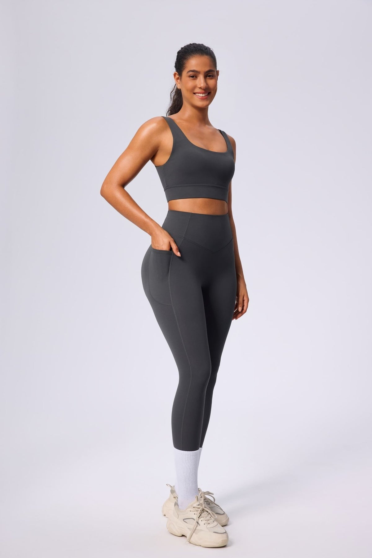 Woman wearing a gray UPF 50+ athletic yoga outfit on a white background