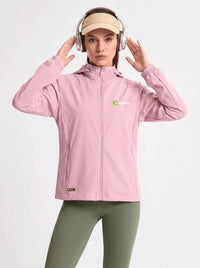 A woman wearing a pink hooded athletic jacket with a small green and white logo on the left chest, olive green leggings, a beige visor, and over-ear headphones, posed against a light gray studio background.