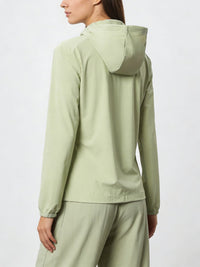 Person wearing a lightgreen jacket with a hood and pants on a white background