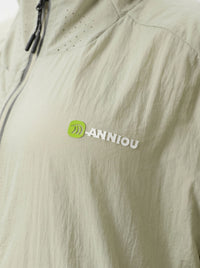 Close-up of a light beige or off-white lightweight jacket fabric with a small green and white ANNIOU logo on the chest.