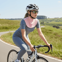 A woman wearing a pink sun-protective scarf was riding her bicycle on the road.