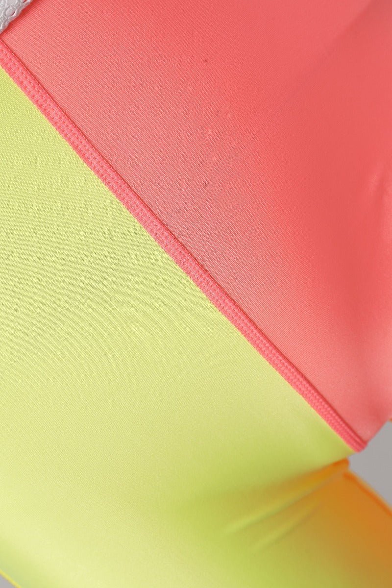 Close - up of a colorful fabric with pink, green, and orange sections.