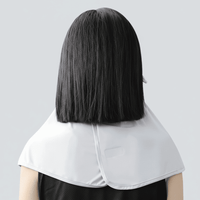 Person wearing a white cape over a black outfit on a light gray background