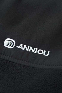 Close - up of a black fabric with 'Anniou' logo embroidered on it.