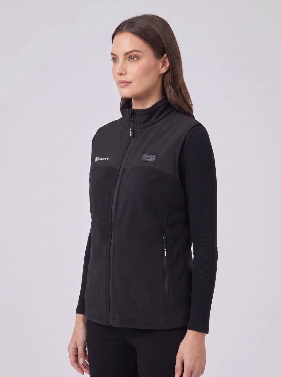 A woman wearing a black zip-front fleece heated vest over a black long-sleeve top.