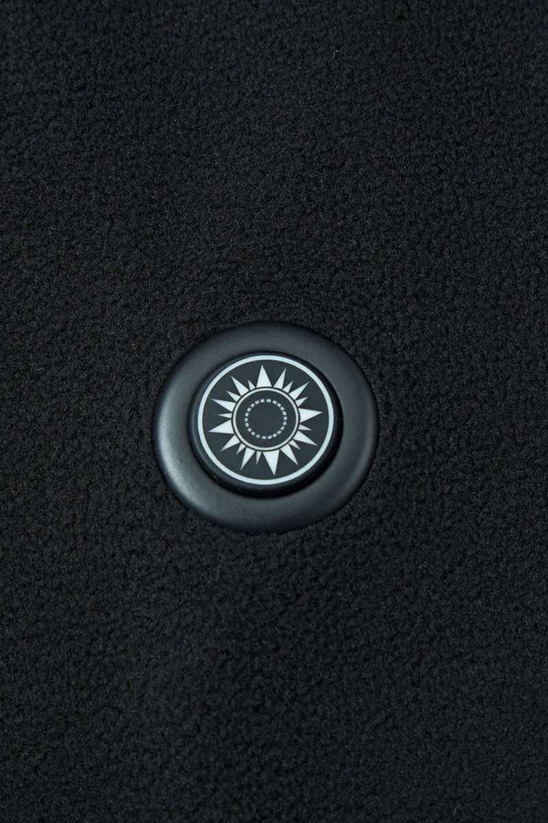 Round button with a sun design on a textured black background