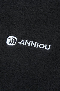 Close - up of a black fabric with 'Anniou' logo embroidered in white.