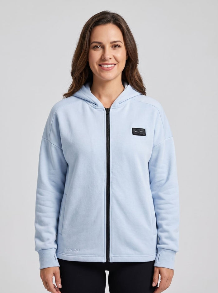A woman wearing a light blue zip-up heated hoodie with a black front zipper.